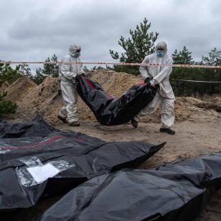 Forensic investigators remove an exhumed body from what is believed to be a mass grave on October 11, 2022 in Lyman, Donetsk oblast, Ukraine.